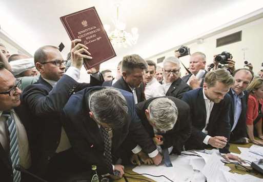 Michal Szczerba of the Civic Platform party holds up a copy of the Polish Constitution as members of the parliament scuffle during the Commission on Justice and Human Rights voting yesterday in Warsaw on the oppositionu2019s amendments to the bill that calls for an overhaul of the Supreme Court.