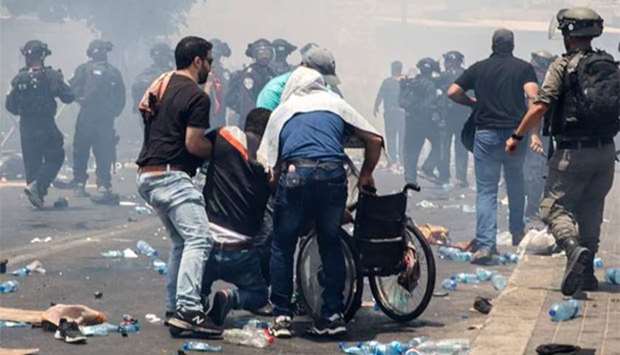 Palestinians lift a man onto a wheelchair during clashes after border guards dispersed Muslim worshippers with tear gas following Friday prayers outside Jerusalem's Old City.