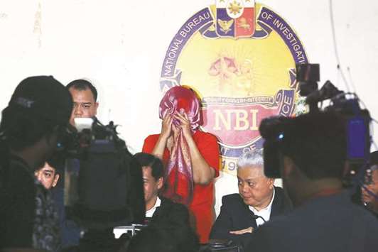 Metrobanku2019s Corporate Service Management Head Maria Victoria Lopez (centre) hides her face during a press conference at the National Bureau of Investigation (NBI)  headquarters in Manila yesterday.