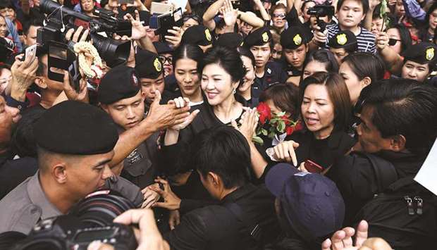 Ousted former Thai prime minister Yingluck Shinawatra greets her supporters as she leaves the Supreme Court in Bangkok, yesterday.