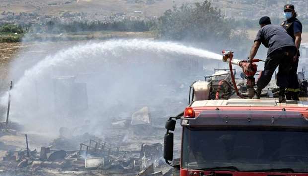 Civil defence members put out fire at a camp for Syrian refugees near the town of Qab Elias, in Lebanon's Bekaa Valley.