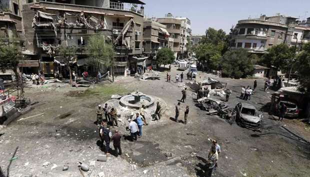 Syrians inspect the site of a suicide bomb attack in the capital Damascus' eastern Tahrir Square district, on July 2, 2017. Syrian state television reported earlier that security forces had intercepted three suicide car bombers on their way into the city, killing two, but the third managed to reach the eastern Tahrir Square district.
