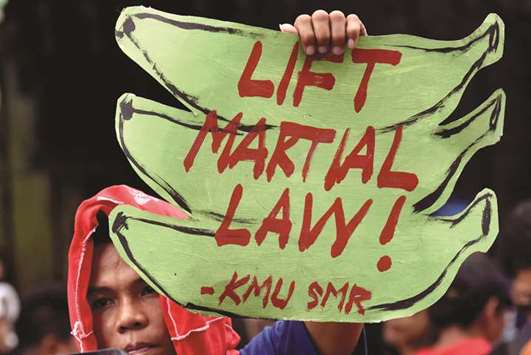 An anti martial law protester holds a placard while protesting during the special session on the extension of martial law at the House of Representatives in Quezon City.