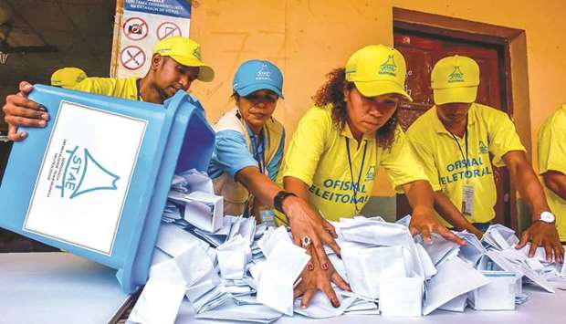 Election officials open a ballot box during counting for the parliamentary election in Dili yesterday.
