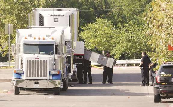 Police officers work on the crime scene after eight people were found dead inside a sweltering 18-wheeler trailer parked behind a Walmart store.