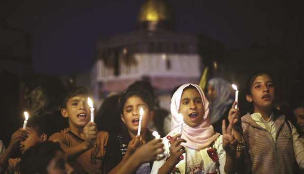 Palestinian children hold candles during a protest against Israelu2019s newly-installed security measures at the entrance to the Al-Aqsa mosque compound, in Khan Younis in the southern Gaza Strip yesterday.
