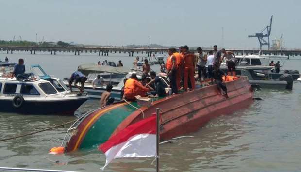 People stand atop a capsized boat near Tarakan, North Kalimantan, Indonesia, in this picture obtained from social media.