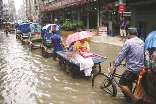 Commuters ride on rickshaws as streets are flooded due to heavy rain in Dhaka yesterday.