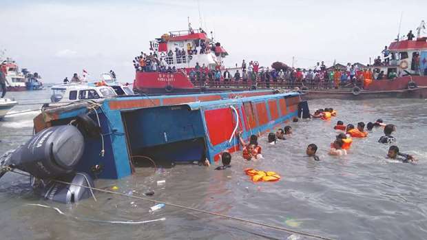 Members of an Indonesian search and rescue team help passengers from a capsized boat in Tarakan yesterday.