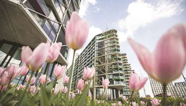 Flowers stand in bloom below blocks of flats that make up a residential development in the Nine Elms area of London on April 3, 2017. MercyCrowd, a new UK-headquartered real estate crowdfunding platform that just set up shop in Qatar, offers for the first time to the people in Qatar opportunities for international real estate purchases through crowdfunding with an emphasis on socially responsible investments.