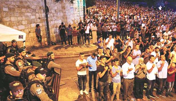 Israeli security forces stand by as Palestinian worshippers pray on Monday night outside Lionsu2019 Gate, an entrance to the Al-Aqsa compound in Jerusalemu2019s Old City.