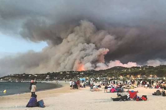 Evacuated people found refuge on the beach and look at a fire burning the forest in Bormes-les-Mimosas, at sunrise. Over 10,000 people, including thousands of holidaymakers, were evacuated from campsites and homes in southern France as firefighters battled the latest in a string of huge blazes along the Mediterranean coast.