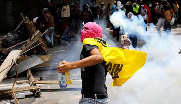 A demonstrator prepares to throw a tear gas canister during a strike called to protest against President Nicolas Madurou2019s government in Caracas, Venezuela, yesterday.