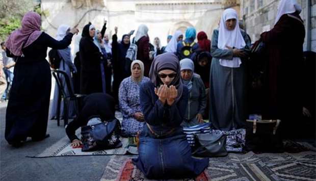 Palestinian women pray as others shout slogans in Jerusalem's Old City on Thursday.
