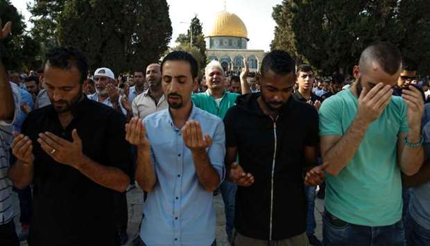 Palestinian Muslims raise their hands in prayer inside the Haram al-Sharif compound  in the old city of Jerusalem, with the Dome of the Rock seen in the background