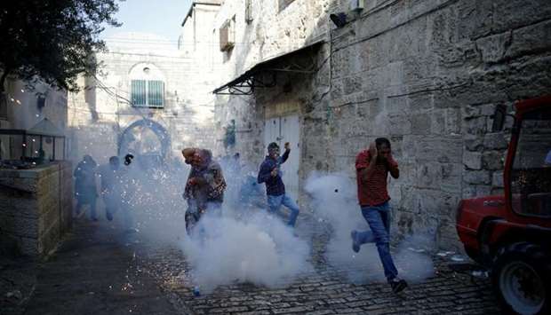 Palestinians react as a stun grenade explodes in a street at Jerusalem's Old city outside the Noble Sanctuary compound, after Israel removed all security measures it had installed.