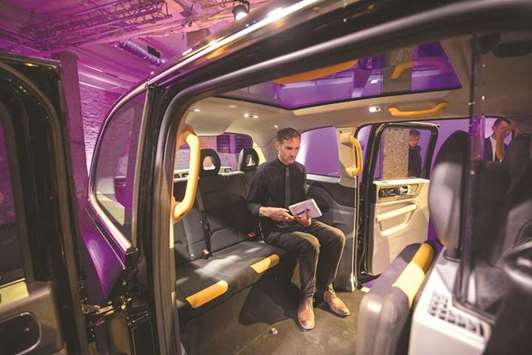 An attendee sits inside the rear of the new TX electric black taxi, manufactured by the London EV, during its unveiling in London on July 11. In London, the government said it will ban sales of the vehicles by 2040, two weeks after France announced a similar plan to reduce air pollution and become a carbon-neutral nation. For the auto industry, the end of an era for fossil-fuel powered cars poses a challenge not everyone is welcoming.