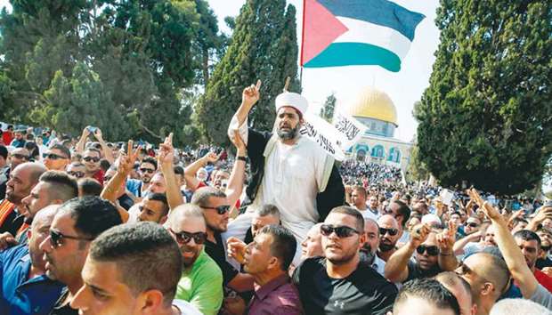 Palestinians carry the director of Al-Aqsa mosque, Sheikh Omar Kiswani (centre), on their shoulders as they shout slogans and wave a national flag, upon entering the Haram al-Sharif compound, in the Old City of Jerusalem yesterday.