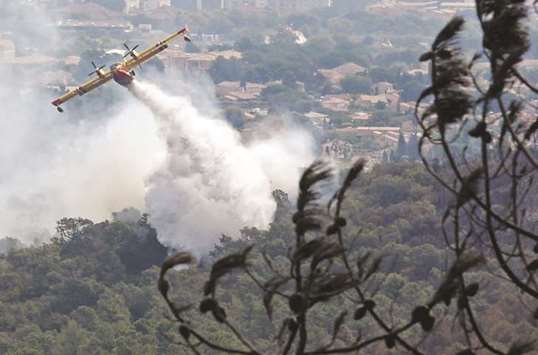 A Canadair firefighting plane releases water to extinguish a wildfire in Bormes-les-Mimosas, in the Var department, France.