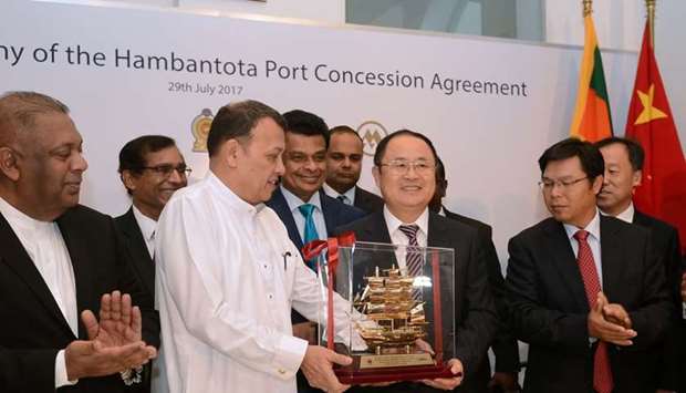 Sri Lanka's Minister of Ports & Shipping Mahinda Samarasinghe (C) exchanges souvenirs with Executive Vice President of China Merchants Port Holdings Dr. Hu Jianhua (3R) during the Hambantota International Port Concession Agreement at a signing ceremony in Colombo.