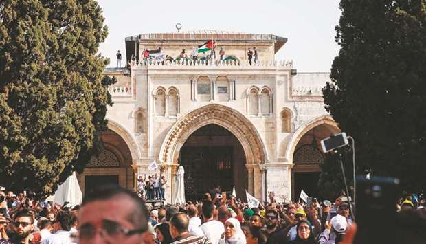Palestinian Muslims wave a national flag from atop Al-Aqsa Mosque in the Haram al-Sharif compound in the old city of Jerusalem. Palestinians ended a boycott and entered the compound site for the first time in two weeks on Thursday.