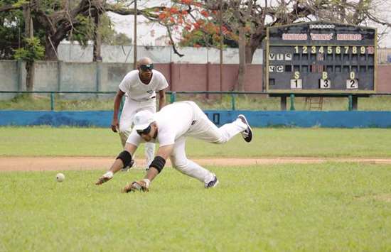 A blind baseball player in Cuba dives to the ground for a ball during a game in Havana. Blind or visually impaired players place bandages over their eyes during games to even the playing field.