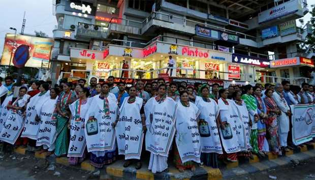 Women wearing aprons bearing anti-GST messages attend a protest