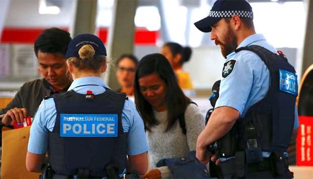 Australian Federal Police officers talk with passengers near the check-in counters at the Sydney Air
