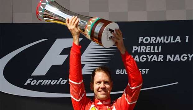 Sebastian Vettel celebrates winning the race on the podium with the trophy.