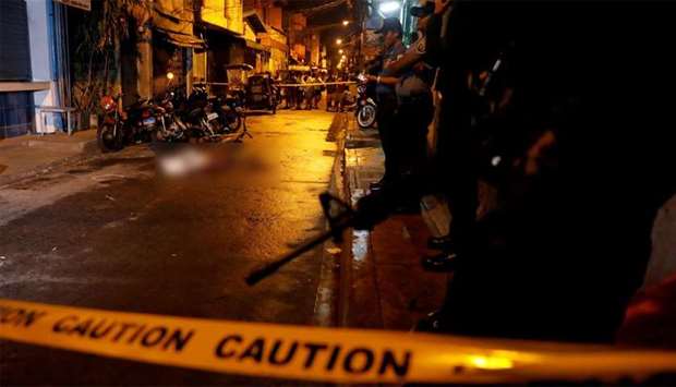 Policemen stand guard near the body of a man killed during a drug related killing in Pasig