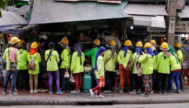 Workers line up to buy food as they take a break in Bangkok