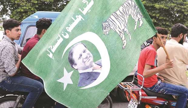 A supporter of ousted Pakistani prime minister Nawaz Sharif carries a party flag during a rally in Rawalpindi. Pakistanu2019s ousted prime  minister Nawaz Sharif named his brother Shahbaz, the chief minister of Punjab province, as his successor and nominated ex-oil  minister Shahid Khaqan Abbasi as an interim premier in a defiant speech.