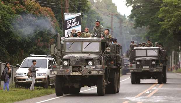 Trucks carrying members of Philippine Marines pass by a town on their way to Marawi city.