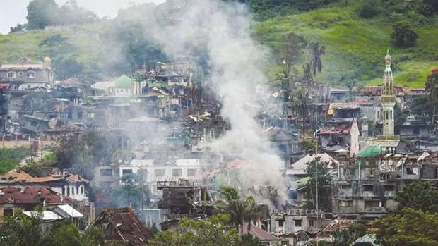 Smoke billows from burning houses as fighting between government troops and militants continues in Marawi on the southern island of Mindanao yesterday.