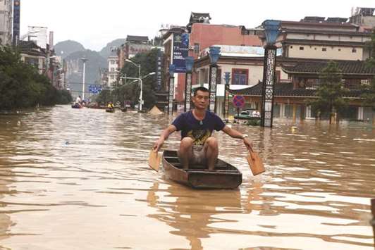 A man makes his way with a wooden boat through a flooded area in Liuzhou, Guangxi province, China.