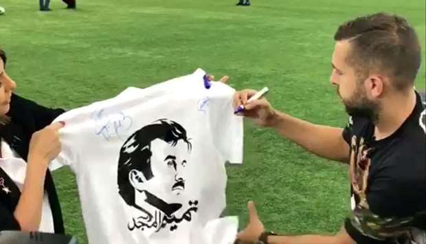 Jordi Alba  signing a T-shirt printed with the image of His Highness the Emir Sheikh Tamim bin Hamad al-Thani.