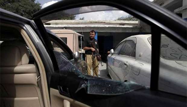 A police officer is seen next to a damaged car of Malik Naveed, a Pakistani regional political party leader, who was killed by unidentified gunmen, at a police station in Quetta on Thursday.
