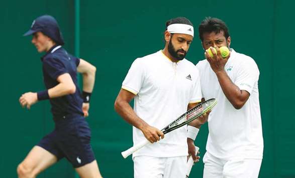 Indiau2019s Leander Paes (R) and his partner Canadau2019s Adil Shamasdin (L) confer between points against Austriau2019s Julian Knowle and Philipp Oswald during their menu2019s doubles first round match at Wimbledon yesterday.