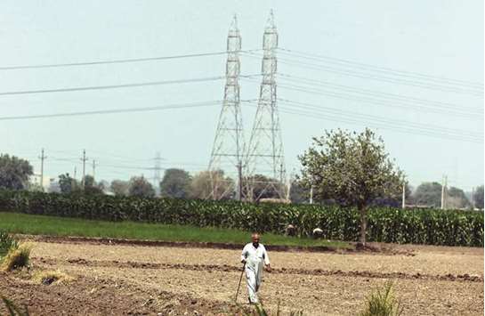 A farmer walks beside electricity pylons near a road which leads to Cairo yesterday. Egypt  yesterday raised household electricity prices by as much as 42%, in a move likely to further anger a population already struggling with soaring costs.