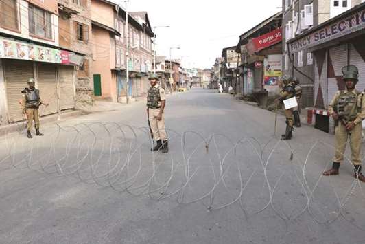 Security forces stand behind a wire barricade in Srinagar city yesterday.
