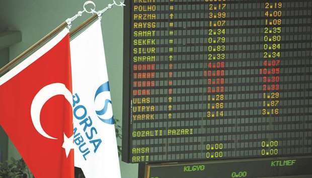 The Turkish national flag (left) and the Borsa Istanbul flag hang alongside financial data displayed on electronic boards inside the Borsa Istanbul, the stock exchange in Istanbul (file). The Borsa Istanbul has rallied 29% this year.