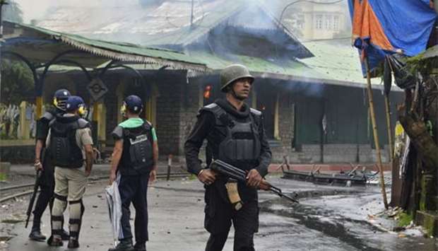 Indian policemen stand near a train station set alight during clashes with Gorkhaland supporters following an indefinite strike called by Gorkha Janamukti Morcha in Sonada near Darjeeling on Saturday.