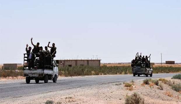 Members of the Syrian pro-government forces riding in vehicles on the road near the Syrian village of Hanna Safar, on the western outskirts of Raqa province.