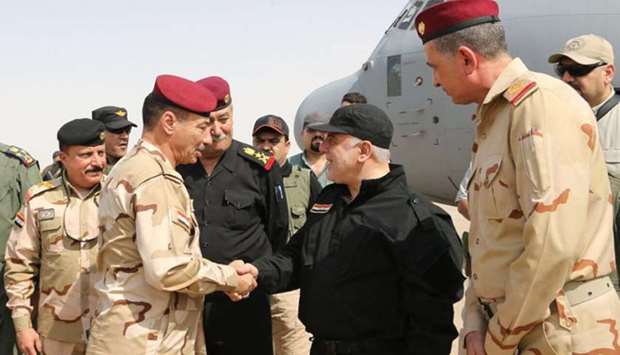 Iraqi Prime Minister Haider al-Abadi (C-R) shaking hands with army officers upon his arrival in Mosul