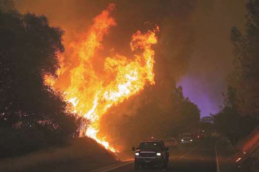 Motorists drive past flames from the u2018Wall Fireu2019 along Forbestown Road in Oroville, California on Saturday.