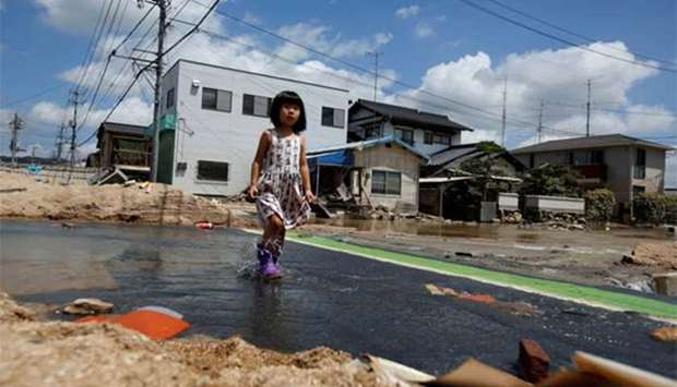 A local resident walks in a flood affected area in Mabi town in Kurashiki on Tuesday.