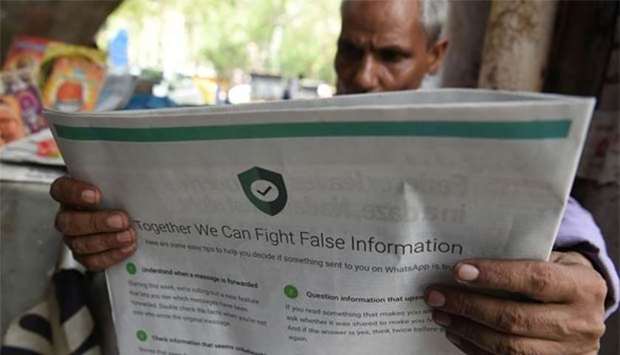 An Indian newspaper vendor reading a newspaper with a full page advertisement from WhatsApp intended to counter fake information, in New Delhi on Tuesday.