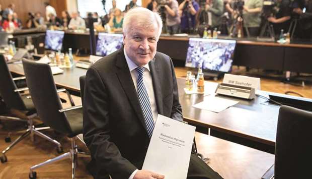 Seehofer poses with a copy of his Masterplan on Migration, ahead a presentation in Berlin.
