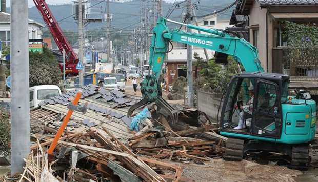 A worker removes the roof blocking a road in the flood hit area Mabicho in Kurashiki, Okayama prefec