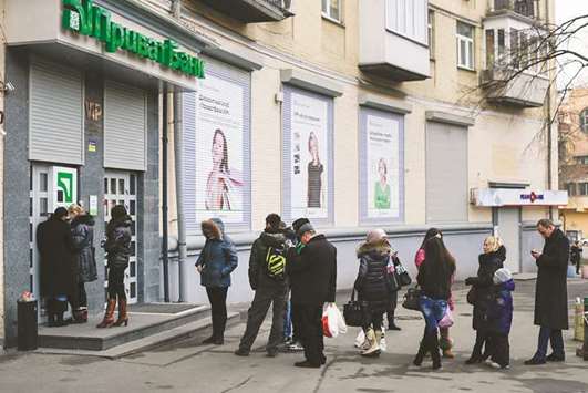 Customers queue to withdraw hyrvnia currency from an automated teller machine outside a Privatbank branch in Kiev. Ukraineu2019s biggest bank does not rule out settling a legal dispute with its former main shareholders out of court, the head of PrivatBanku2019s supervisory board said.
